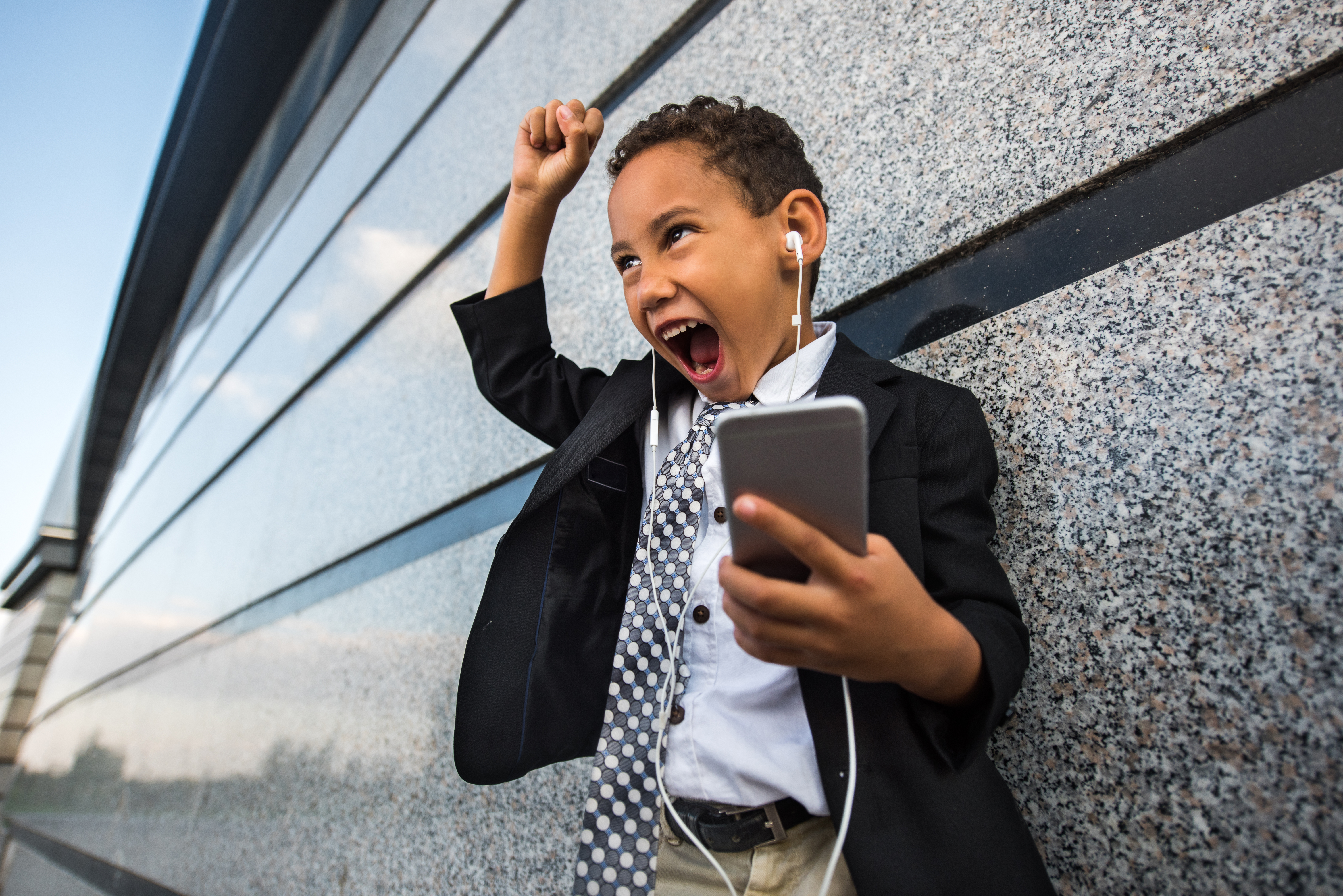 Cheerful African American business boy singing while listening MP3 player.
