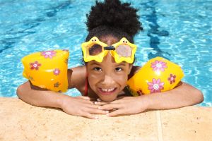 Girl with floaties and goggles in swimming pool