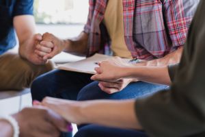 Diverse group of adults sitting in circle holding hands